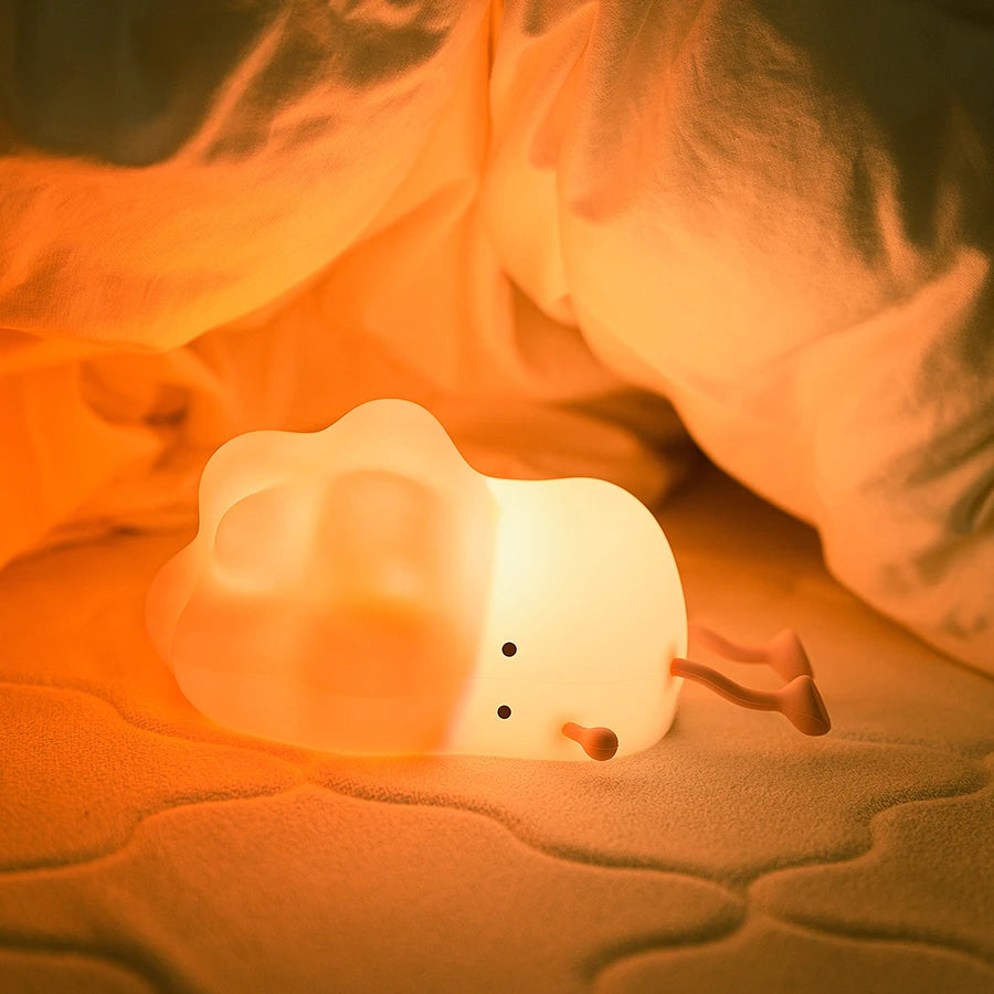 White brocolii-shaped night light on a soft surface with a warm glow