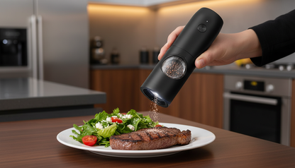 Person seasoning a steak with a pepper grinder in a kitchen setting