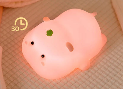 Pink hippo-shaped night light on a textured surface with text indicating adjustable brightness.