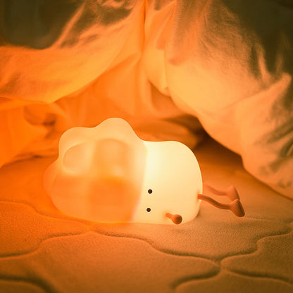 White brocolii-shaped night light on a soft surface with a warm glow