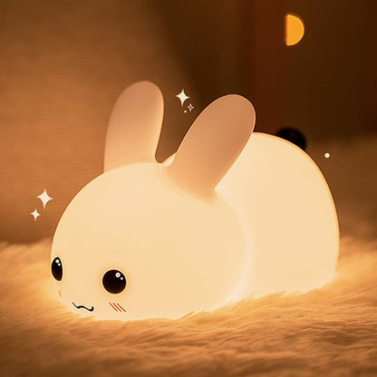 Cute rabbit-shaped night light emitting a warm glow on a soft surface.